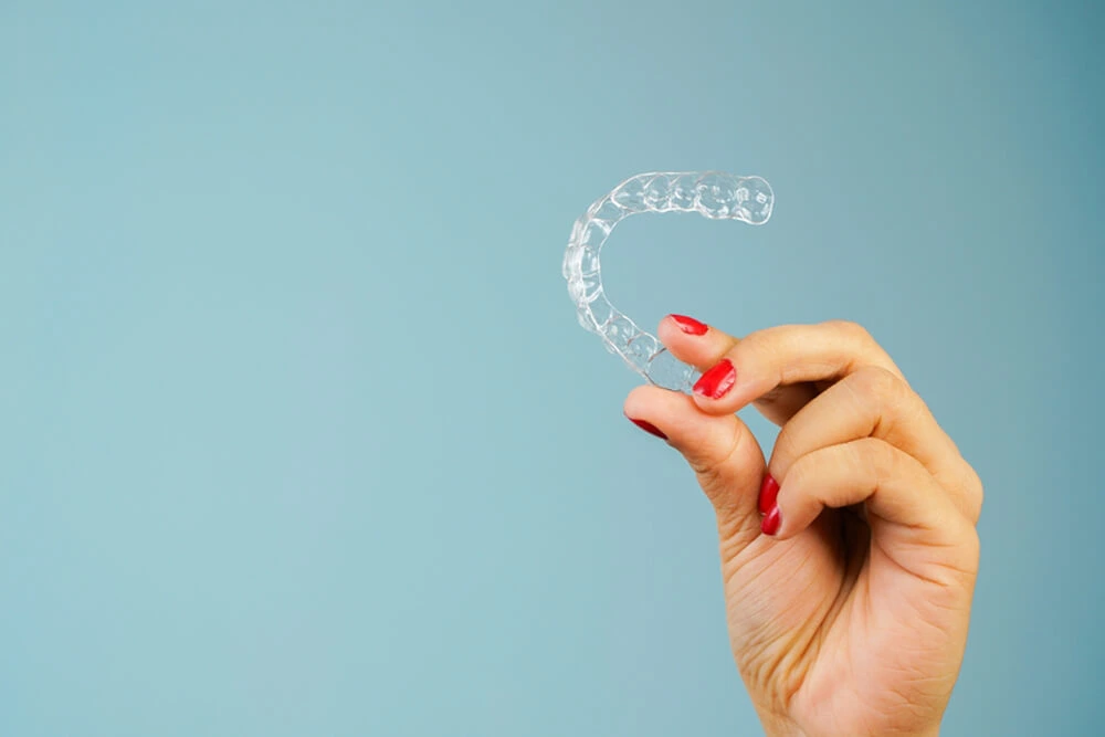 Hand holding a clear dental aligner.
